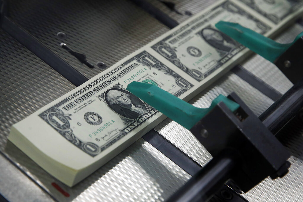 FILE- In this Nov. 15, 2017, file photo, new $1 bills with the signatures of U.S. Treasurer Jovita Carranza and Treasury Secretary Steven Mnuchin are cut and stacked at the Bureau of Engraving and Printing in Washington. 