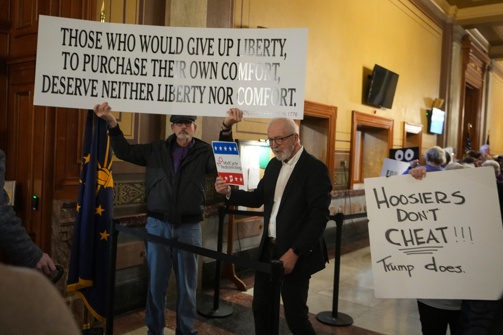 Protestors hold signs outside the Indiana Senate chamber before a vote to redistrict the state's congressional map at the Statehouse in Indianapolis, Thursday, Dec. 11, 2025. 