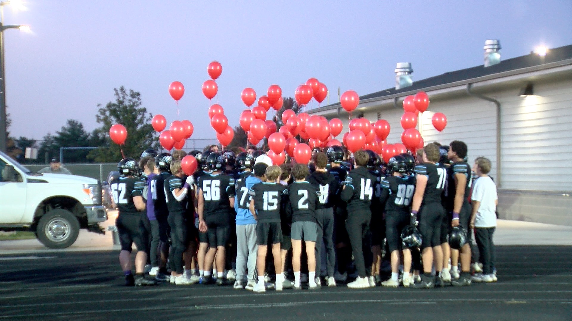 Elkhorn North football players release red balloons for head coach Sam Stanley's son Grant, who died from congenital heart disease at 11 months old.