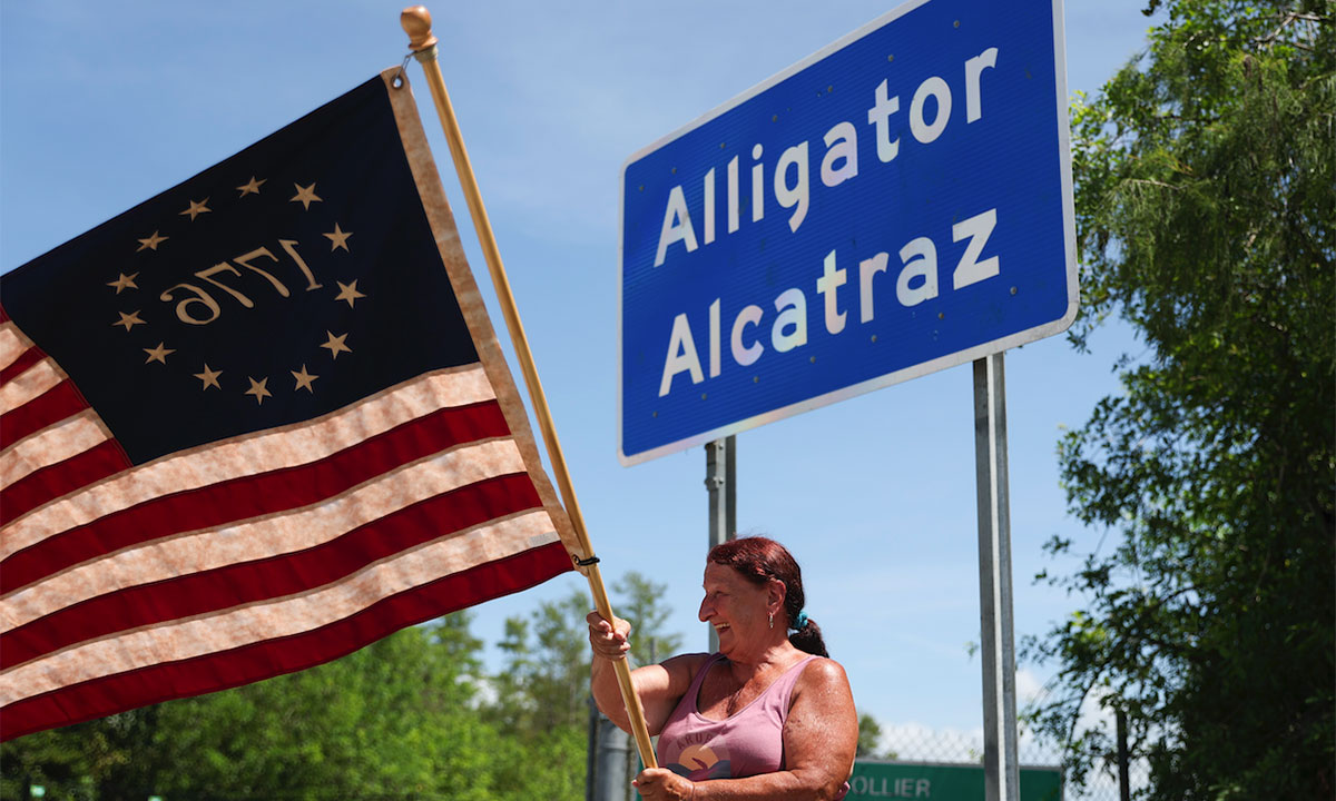 Woman in front of Alligator Alcatraz sign 