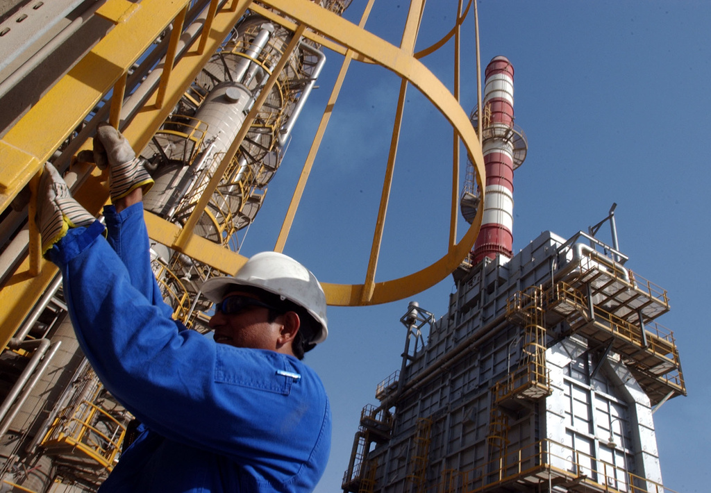FILE - An oil technician climbs down a tower at a refinery in Jebel Ali, United Arab Emirates, about 30 kilometers (18 miles) south of Dubai, in March 2004. 