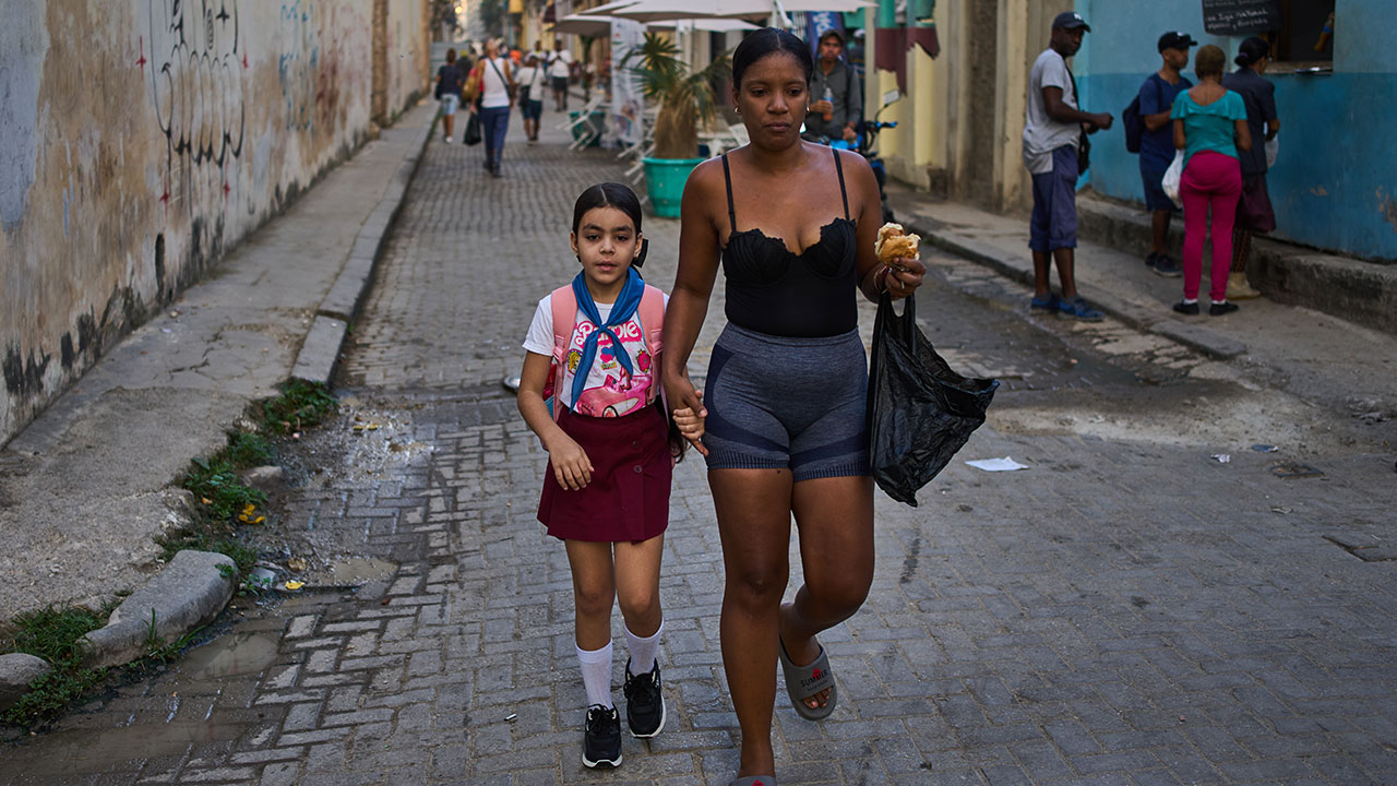 A woman accompanies a student to school in Havana, Cuba, Friday, March 13, 2026.  