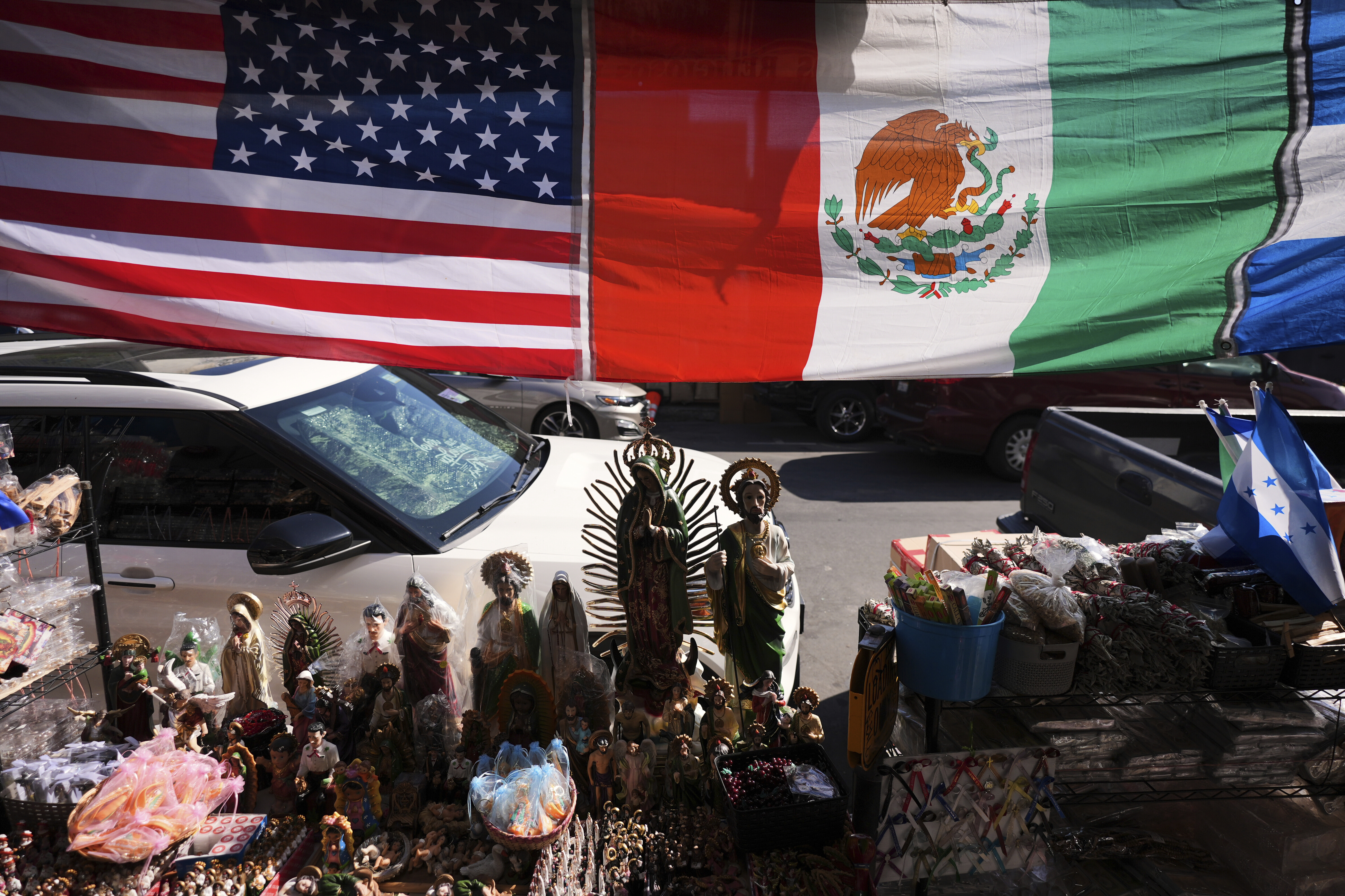 Religious figurines and goods are displayed beneath American and Mexican flags in the Toy District of Los Angeles, Wednesday, April 9, 2025.
