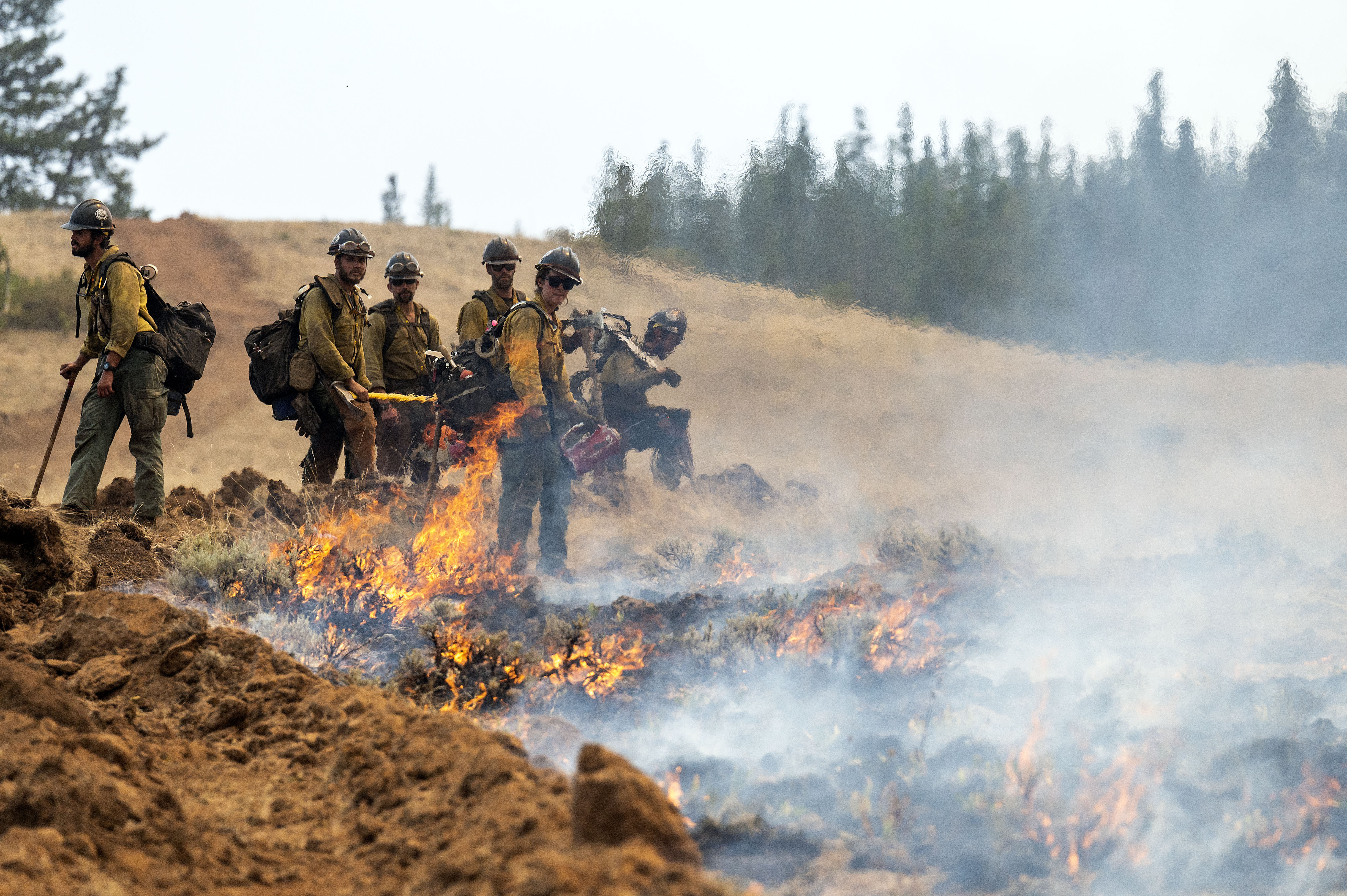 FILE - A wildland fire crew looks on after setting a fire line on Harlow Ridge above the Lick Creek Fire, July 12, 2021, south of Asotin, Wash.