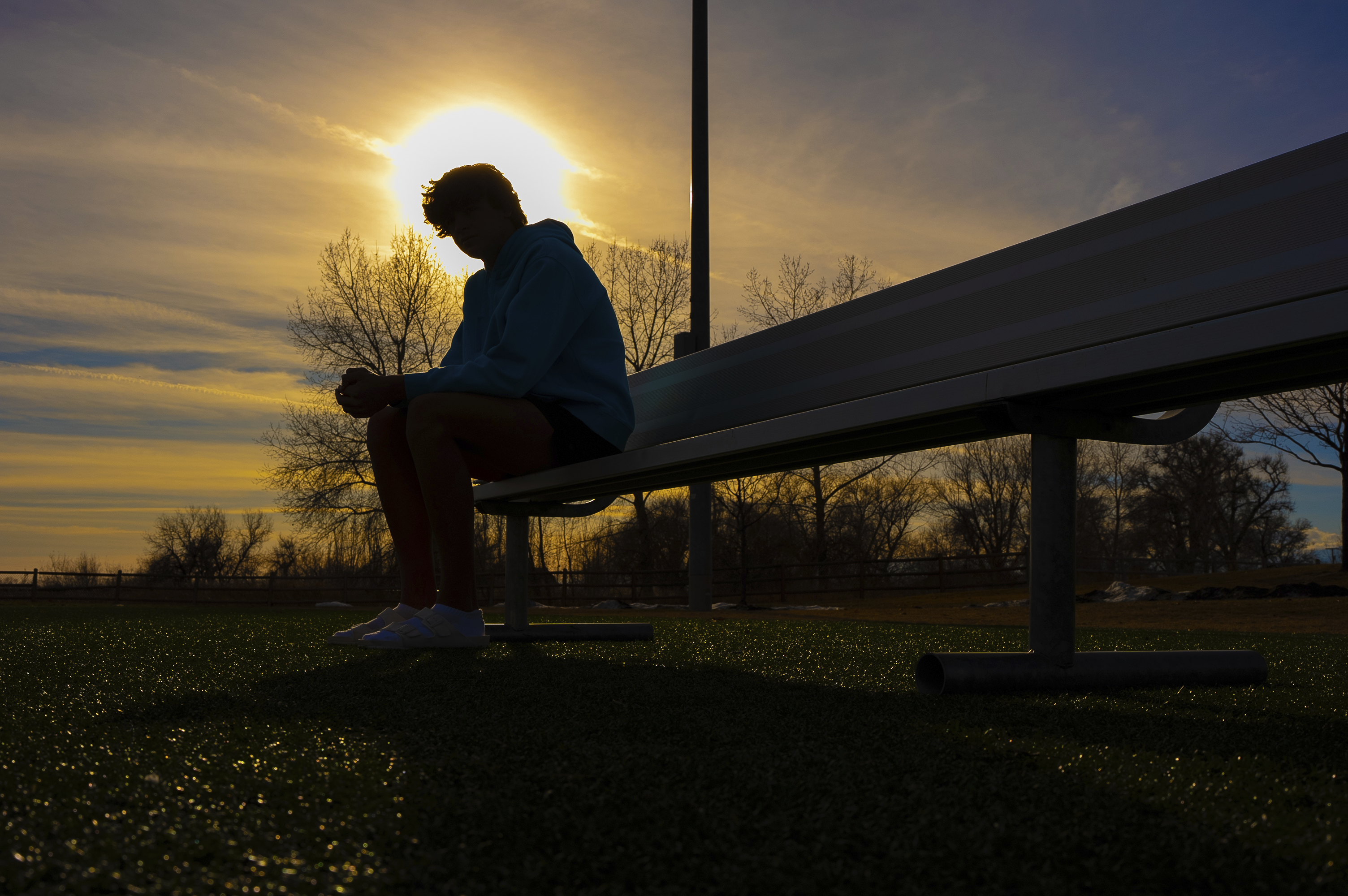 A 16-year-old swimmer sits on a bench at a park near his home about 40 miles north of Denver on Dec. 22, 2023. The Associated Press is not using the teen's name because he is a minor.