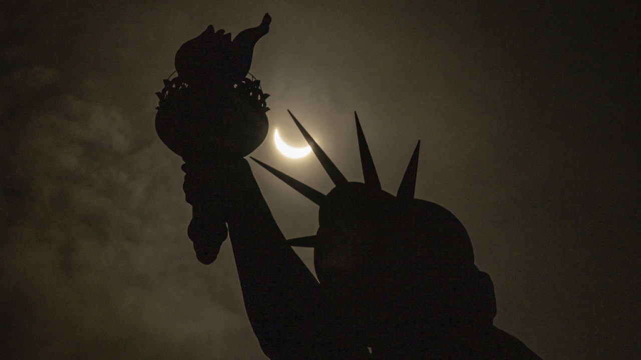 The moon partially covers the sun behind the Statue of Liberty during the solar eclipse on April 8, 2024.