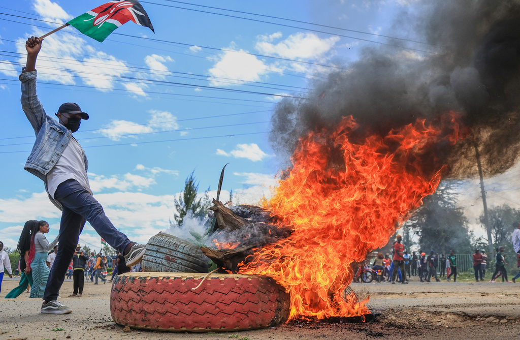 A protester raises a Kenyan flag near a burning barricade during a demonstration against a proposed Ebola quarantine center to be established by the United States at Laikipia Air Base in Nanyuki, Kenya, Monday, June 1, 2026.