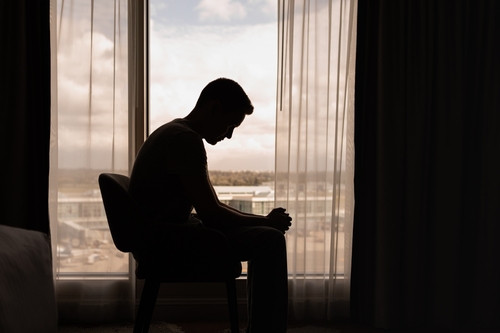 Silhouette of a man sitting alone in a room.
