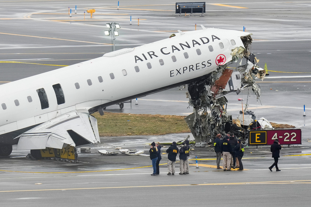 Officials with the National Transportation Safety Board investigate the site on March 23, 2026, where an Air Canada jet came to rest after colliding with a Port Authority firetruck at LaGuardia Airport, shortly after landing in New York.