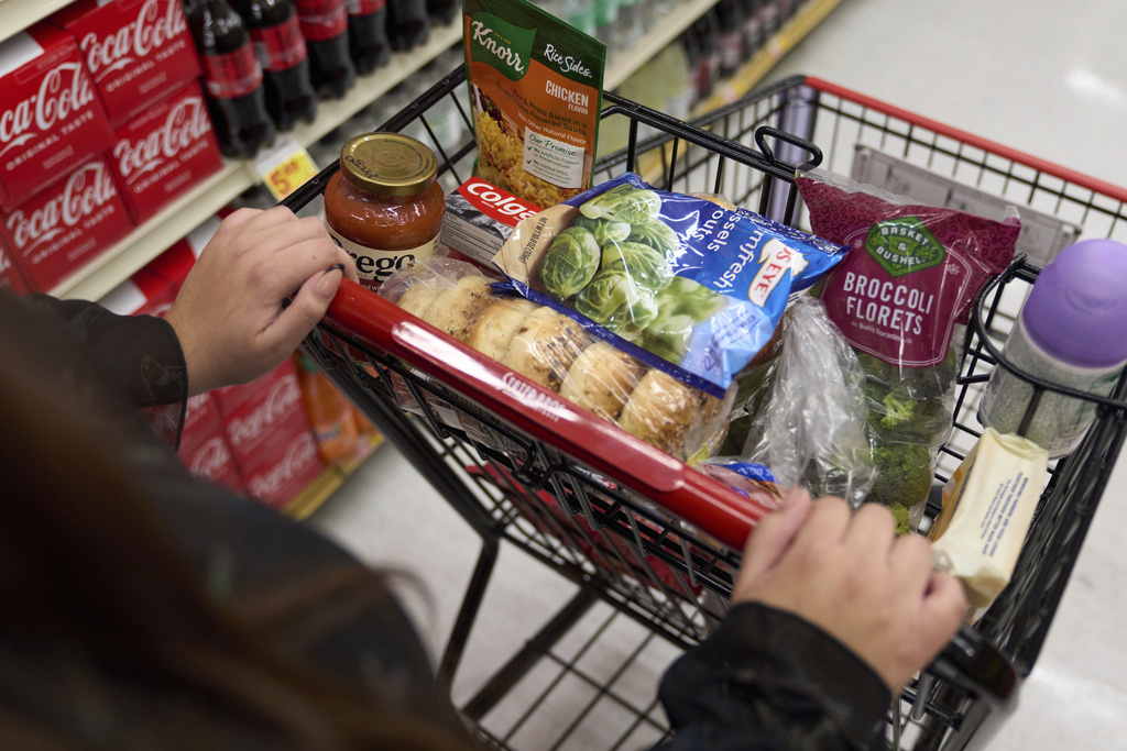 A food shopper pushes a cart of groceries at a supermarket.