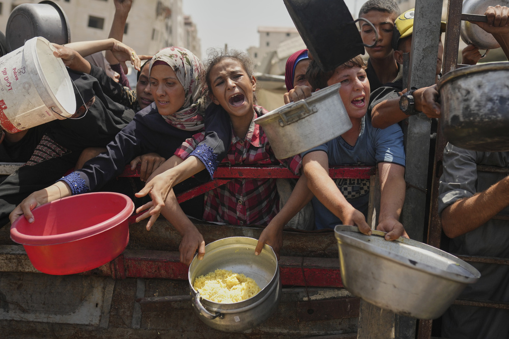  Palestinians struggle to get donated food at a community kitchen in Gaza City, northern Gaza Strip, Saturday, Aug. 16, 2025. 
