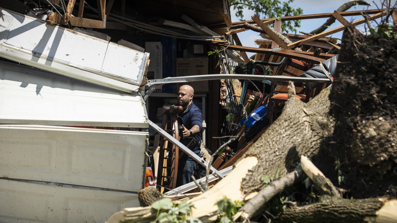 A resident cleans up after a tornado touched down in suburban Chicago Monday, June 21, 2021.