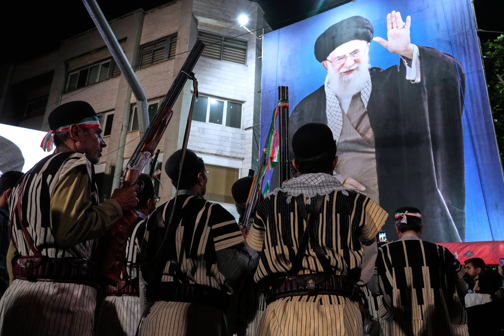 Bakhtiari nomads, wearing traditional dress, hold their guns during a pro-government gathering near the residence where former Iranian Supreme Leader Ayatollah Ali Khamenei, shown on a banner, was killed in U.S. and Israeli strikes on Feb. 28, in Tehran, Iran, Monday, May 18, 2026. 
