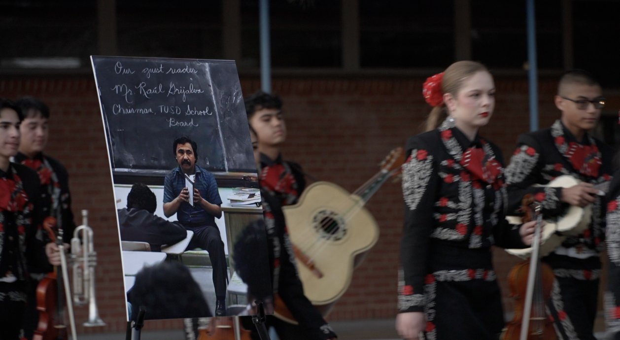 Mariachi Rayos del Sol de Tucson High walk past a sign of Grijalva 