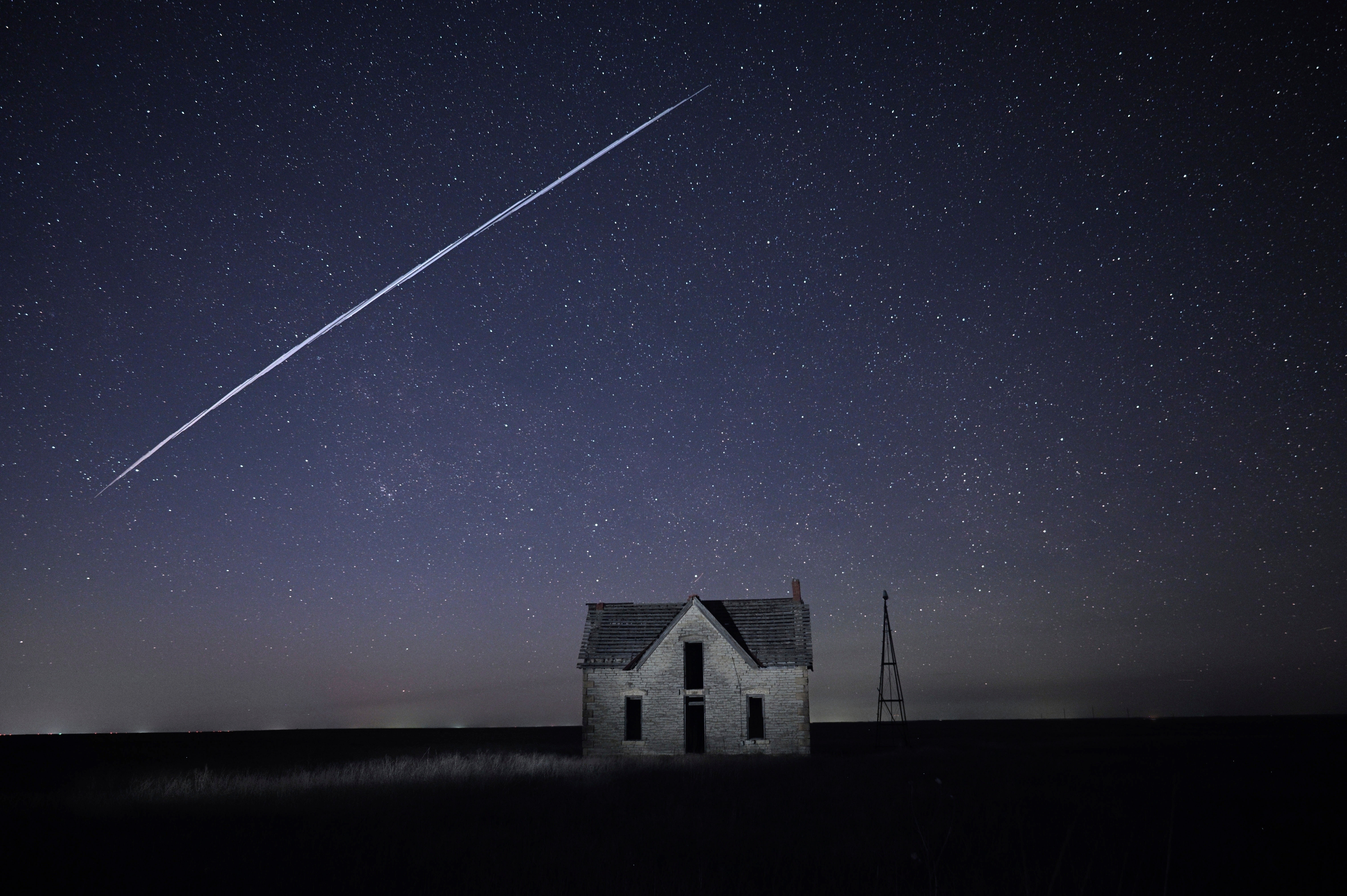 FILE - In this long exposure photo, a string of SpaceX StarLink satellites passes over an old stone house near Florence, Kan., on May 6, 2021.