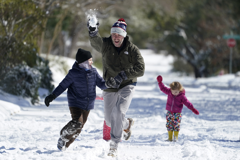 Craig Crow, center, throws snowballs as he plays in the snow with his children and neighbors.