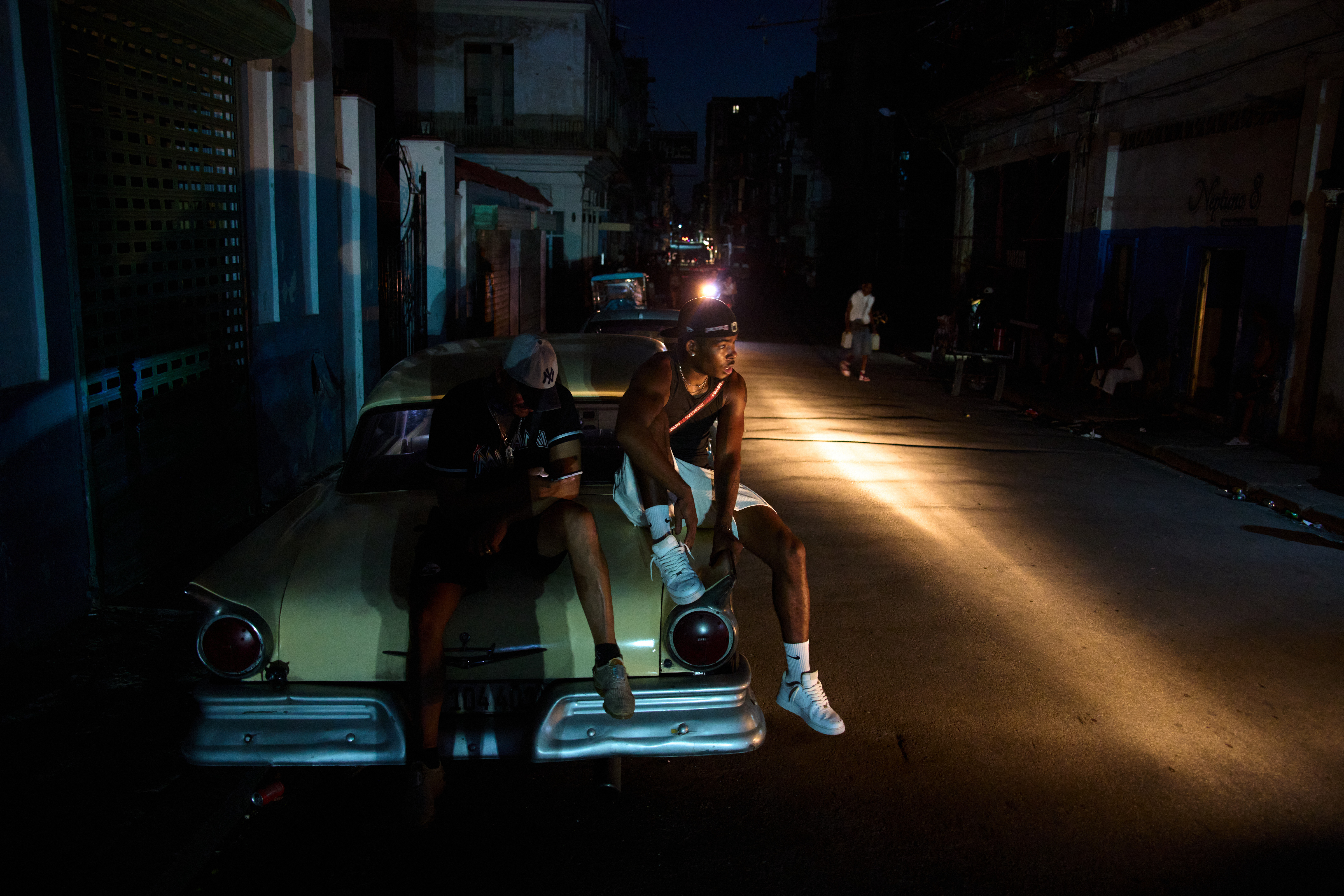 Men sit on the trunk of a car during a blackout in Havana, Cuba, Tuesday, July 14, 2026. 