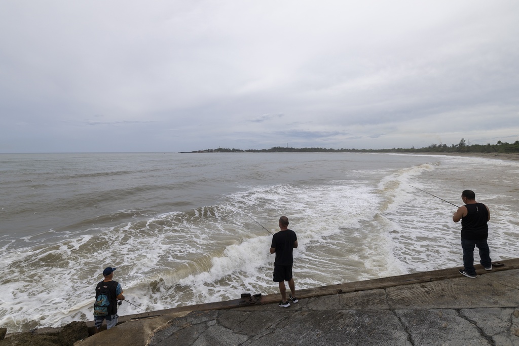 People fish along the shore in Arecibo, Puerto Rico, as Hurricane Erin brings rains to the island, Sunday, Aug. 17, 2025. 