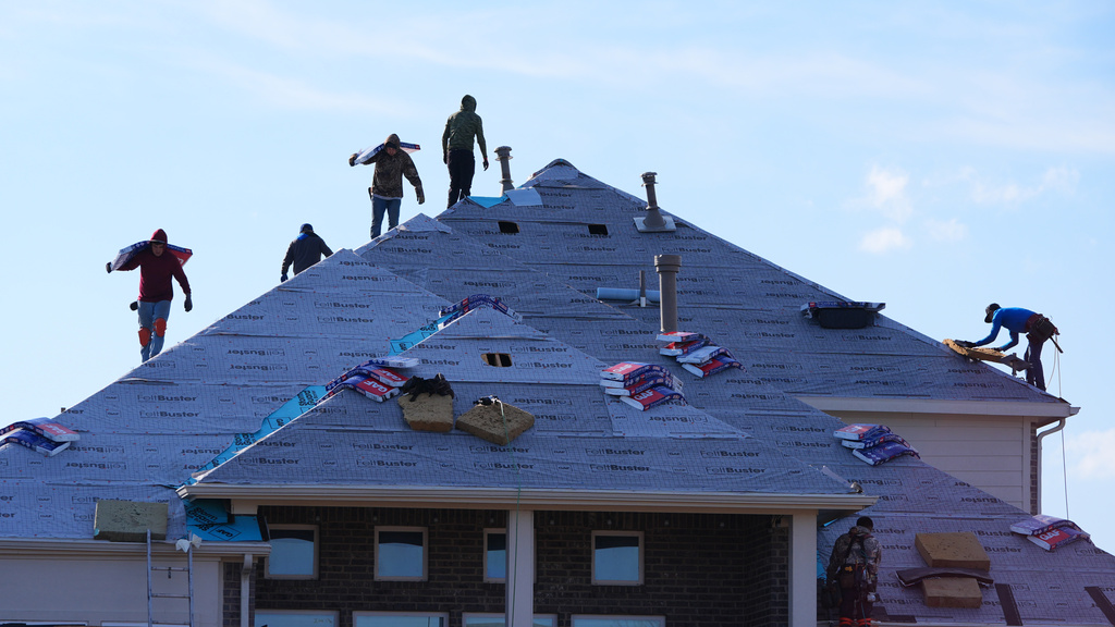 Roofers work atop a house in Anna, Texas, Thursday, Dec. 18, 2025. 