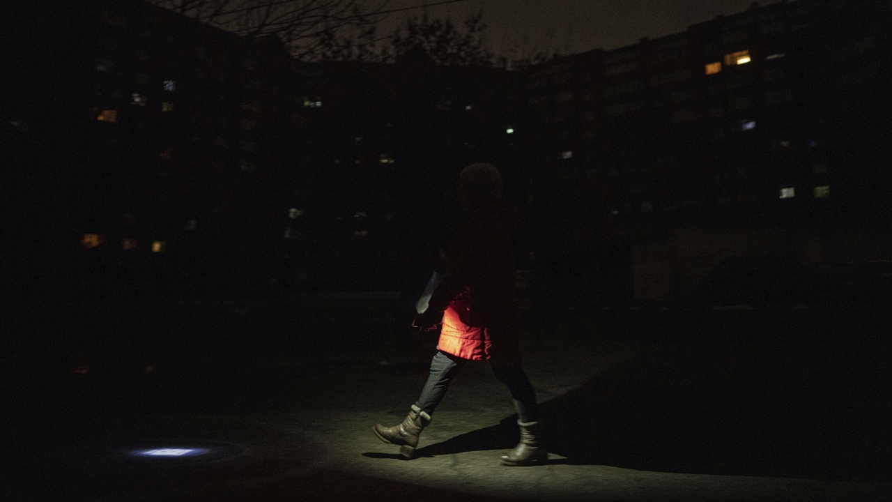 A woman lights up the road with a flashlight during blackout in Kyiv, Ukraine.