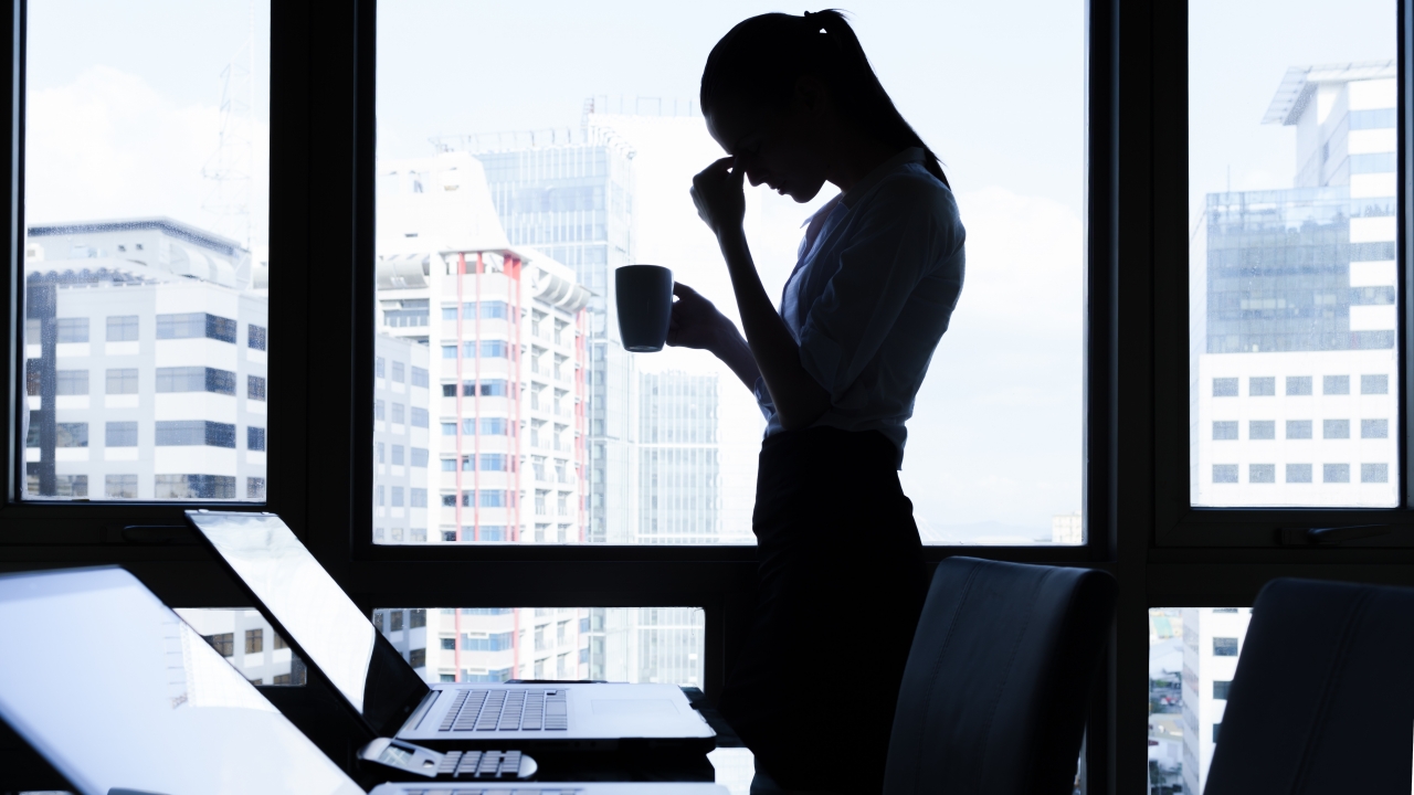 Silhouette of office worker at her desk in a stressed position