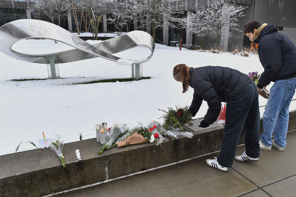 People place flowers at a makeshift memorial, Sunday, Dec. 14, 2025, on the campus of Brown University, not far from where a shooting took place on Saturday, in Providence, R.I. 