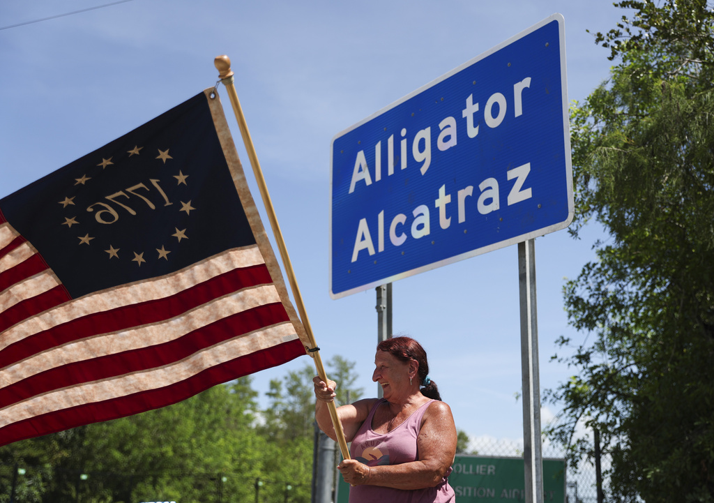 Rana Mourer waves an American flag outside of the Dade-Collier Training and Transition facility, Saturday, July 12, 2025 in Ochopee, Fla.