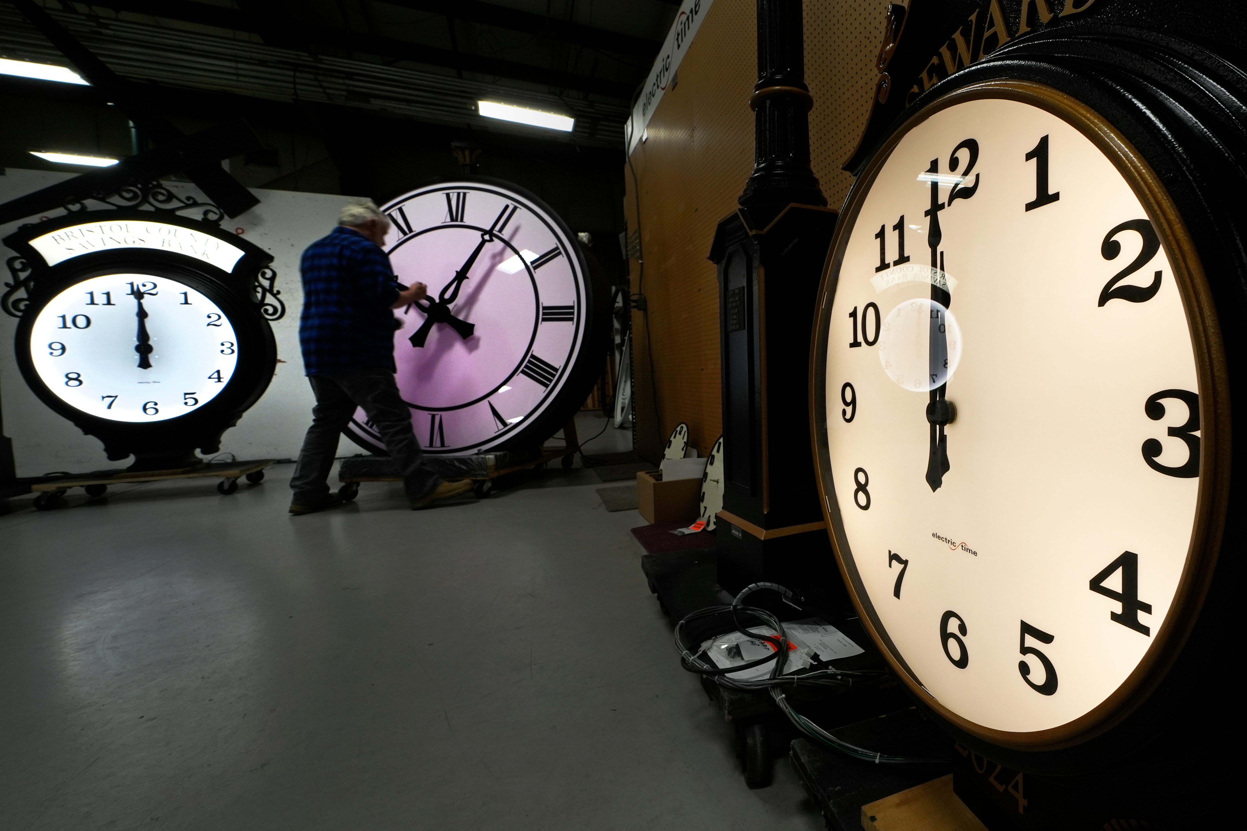 FILE - Clockmaker Scott Gow adjusts the hands of a clock at the Electric Time Company, Oct. 30, 2024, in Medfield, Mass. 