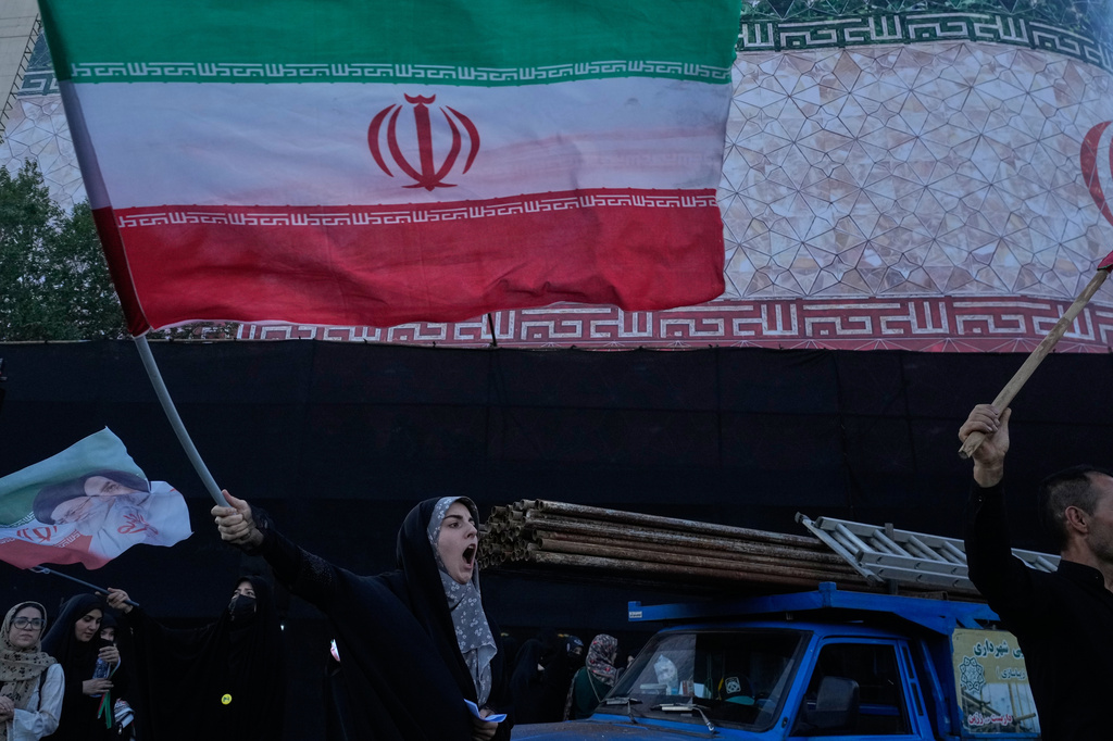 A woman waves an Iranian flag as she chants slogans against Iran and U.S. talks at the Islamic Revolution Square in Tehran, Iran, Sunday, June 14, 2026. 