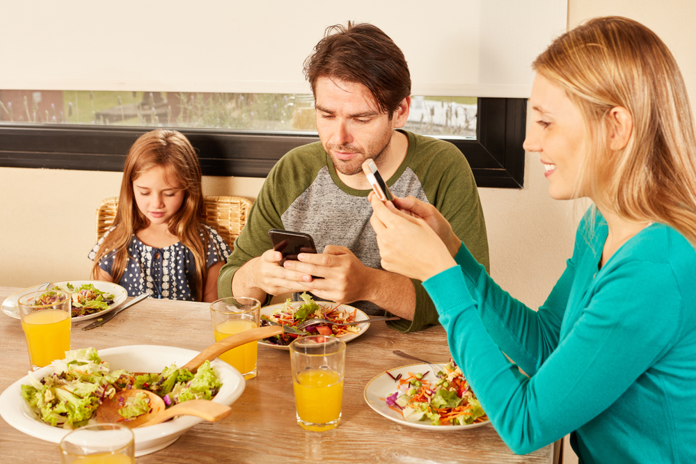 Parents,And,Daughter,Using,Smartphone,And,Cellphone,Together,At,The