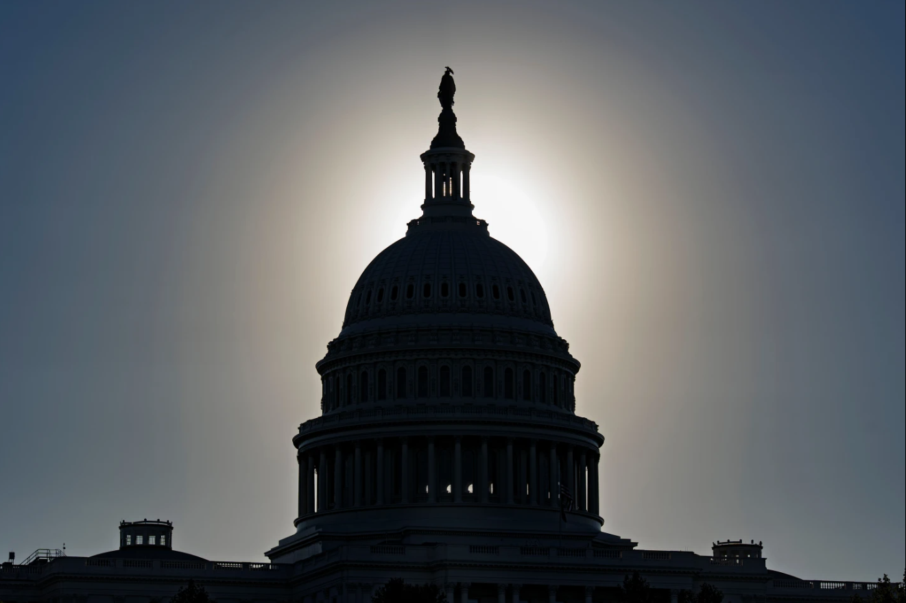 The U.S. Capitol is silhouetted by the dark glare of the morning sun as a government shutdown begins its tenth day, in Washington, Friday, Oct. 10, 2025.