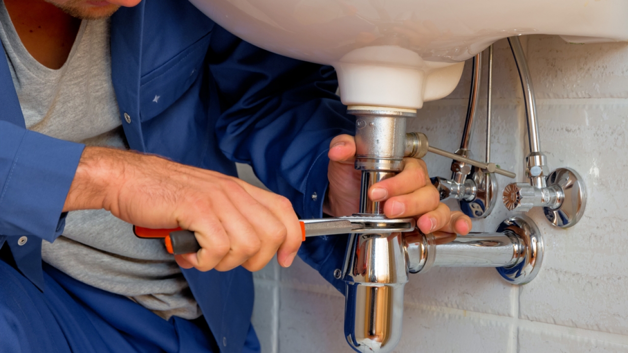 A man fixes the plumbing on a sink.