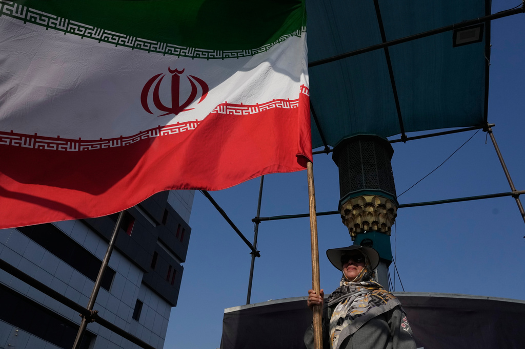 A woman holds an Iranian flag as part of a pro-government campaign in downtown Tehran, Iran, Monday, Aug. 17, 2026. 