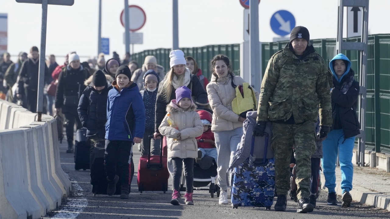 A Polish border guard assists refugees from Ukraine as they arrive to Poland