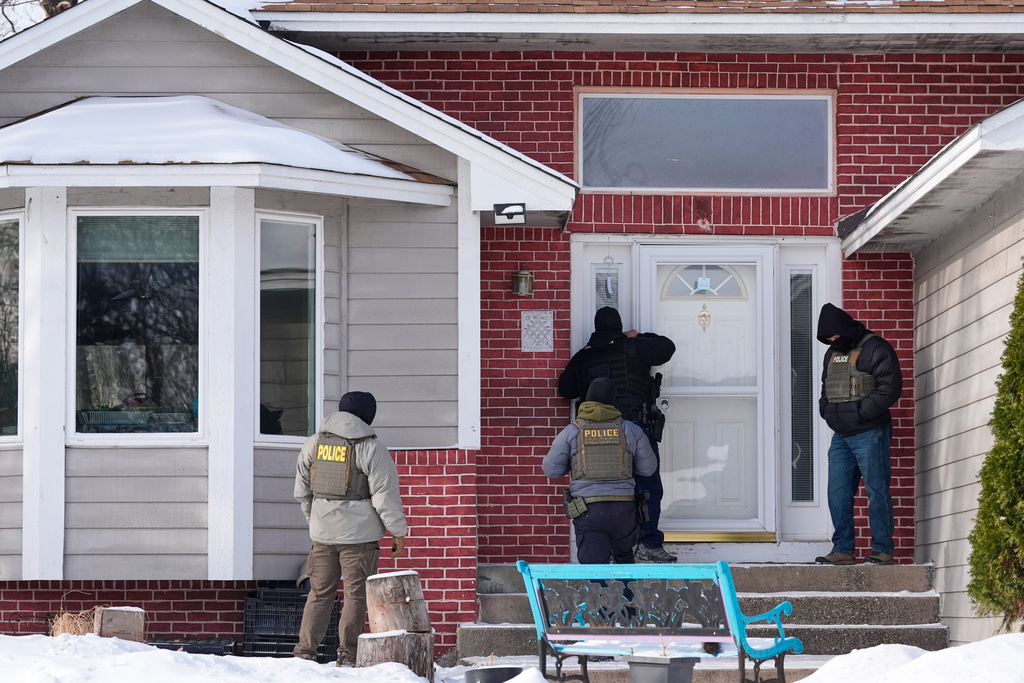 Federal immigration officers look through the window of a home Tuesday, Jan. 20, 2026, in Maplewood, Minn. 