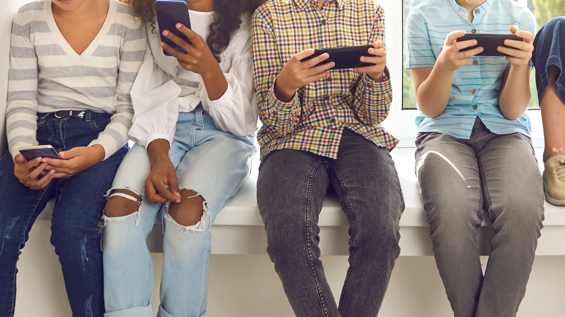 Stock image of kids on their cell phones.