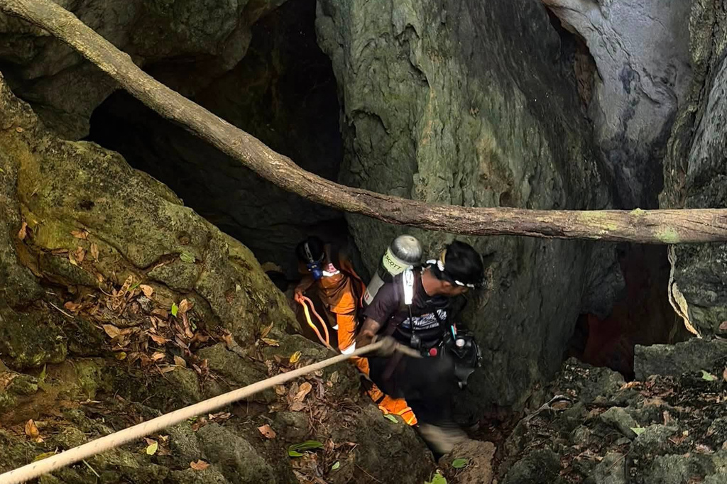 In this image released by Metta Tham Rescue Kalasin, rescuers try to reach people who have been trapped in a cave in Xaisomboun province, Laos, Tuesday, May 26, 2026. 