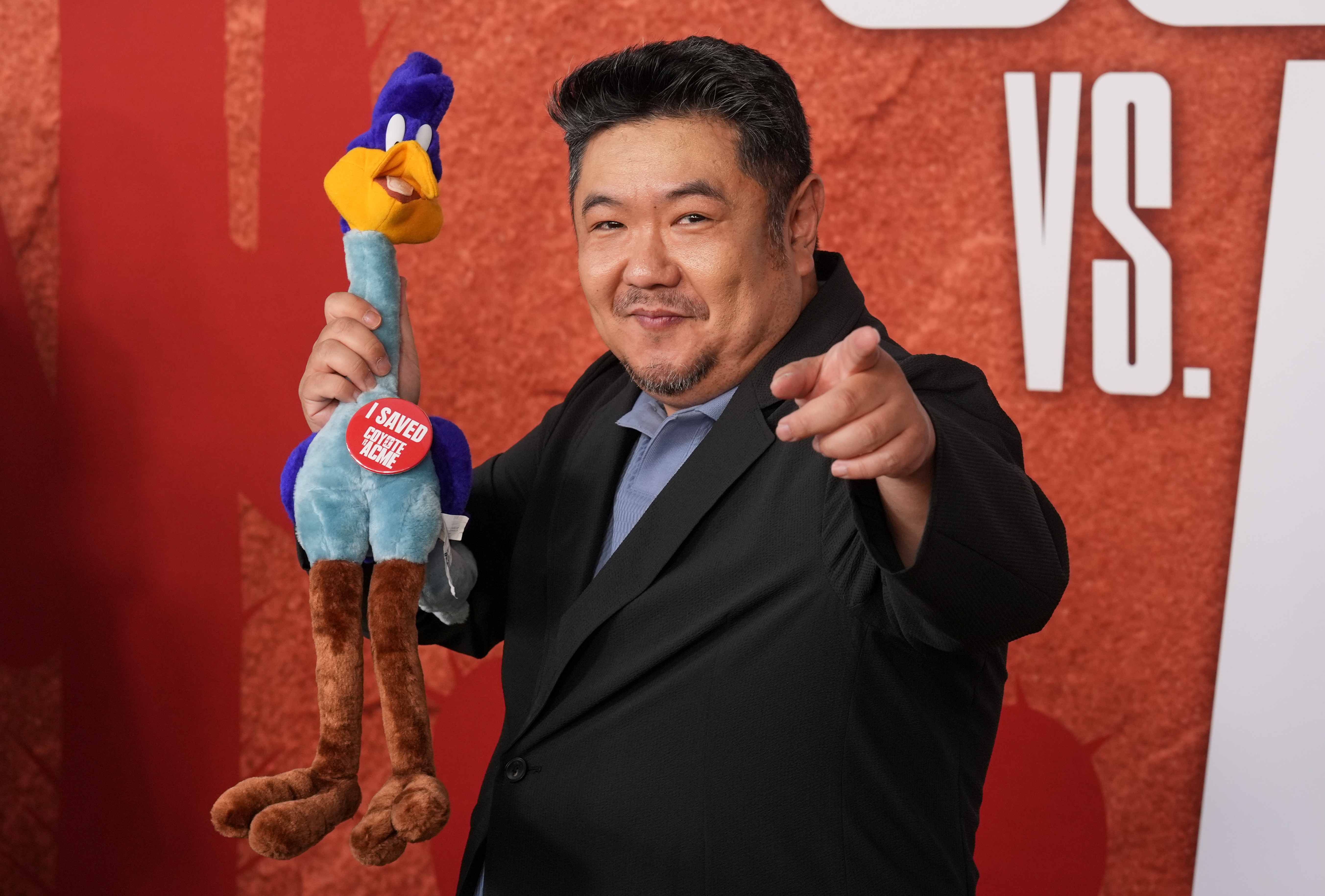 FILE - Cast member Eric Bauza holds a Road Runner stuffed animal as he arrives at the premiere of the film "Coyote vs. Acme" in Los Angeles on Aug. 26, 2026. 