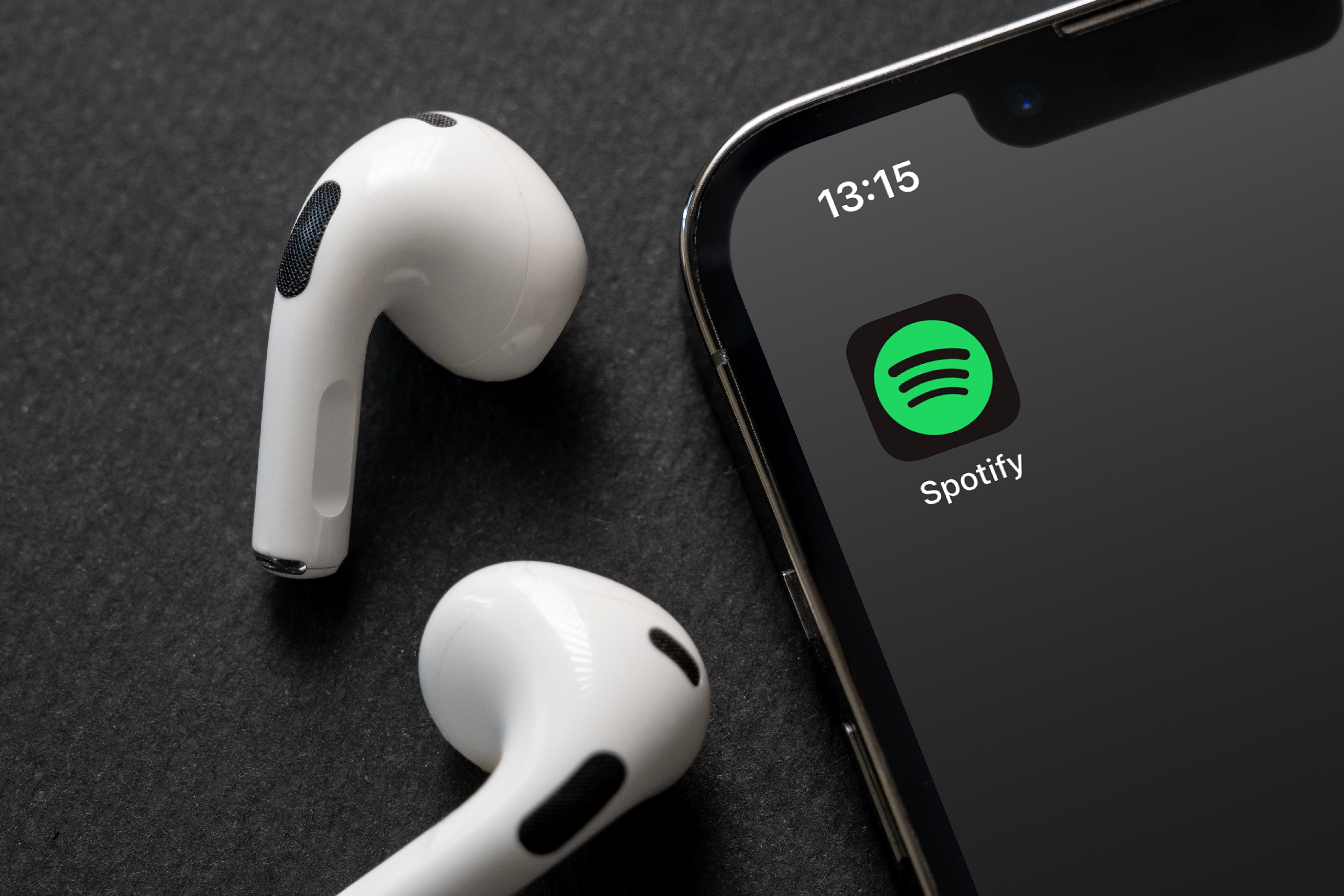 Spotify logo on a phone next to airpods.