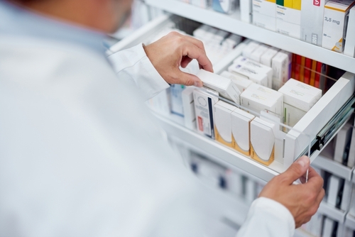 Pharmacist handling a drawer of various medications.