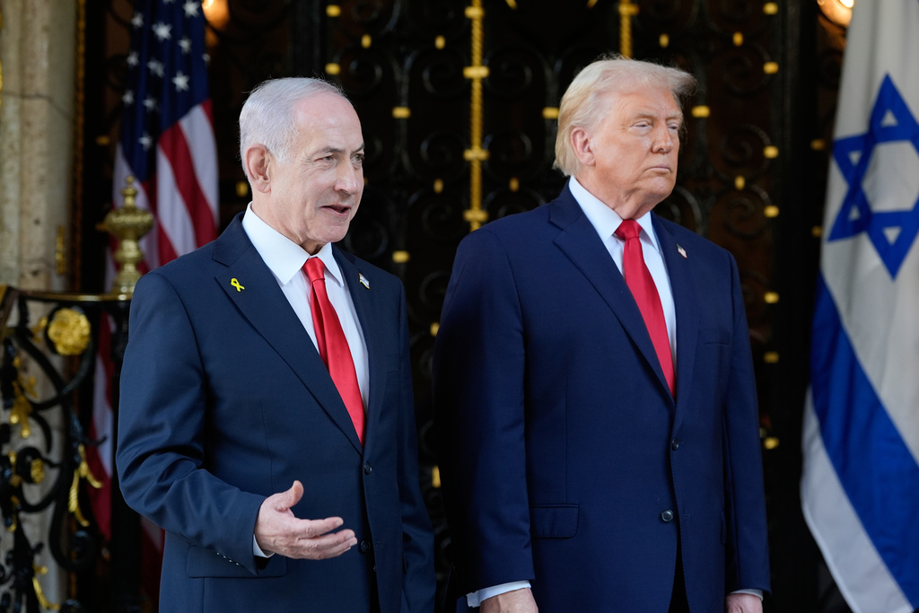 Israel's Prime Minister Benjamin Netanyahu speaks to reporters as President Donald Trump listens at the Mar-a-Lago club, Monday, Dec. 29, 2025, in Palm Beach, Fla. 