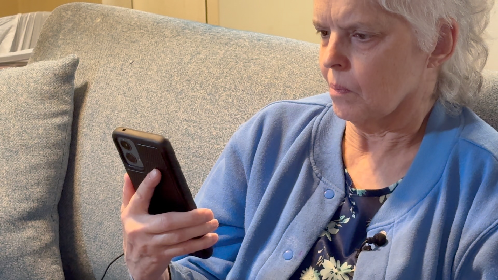 Woman sitting on couch while playing music on cell phone