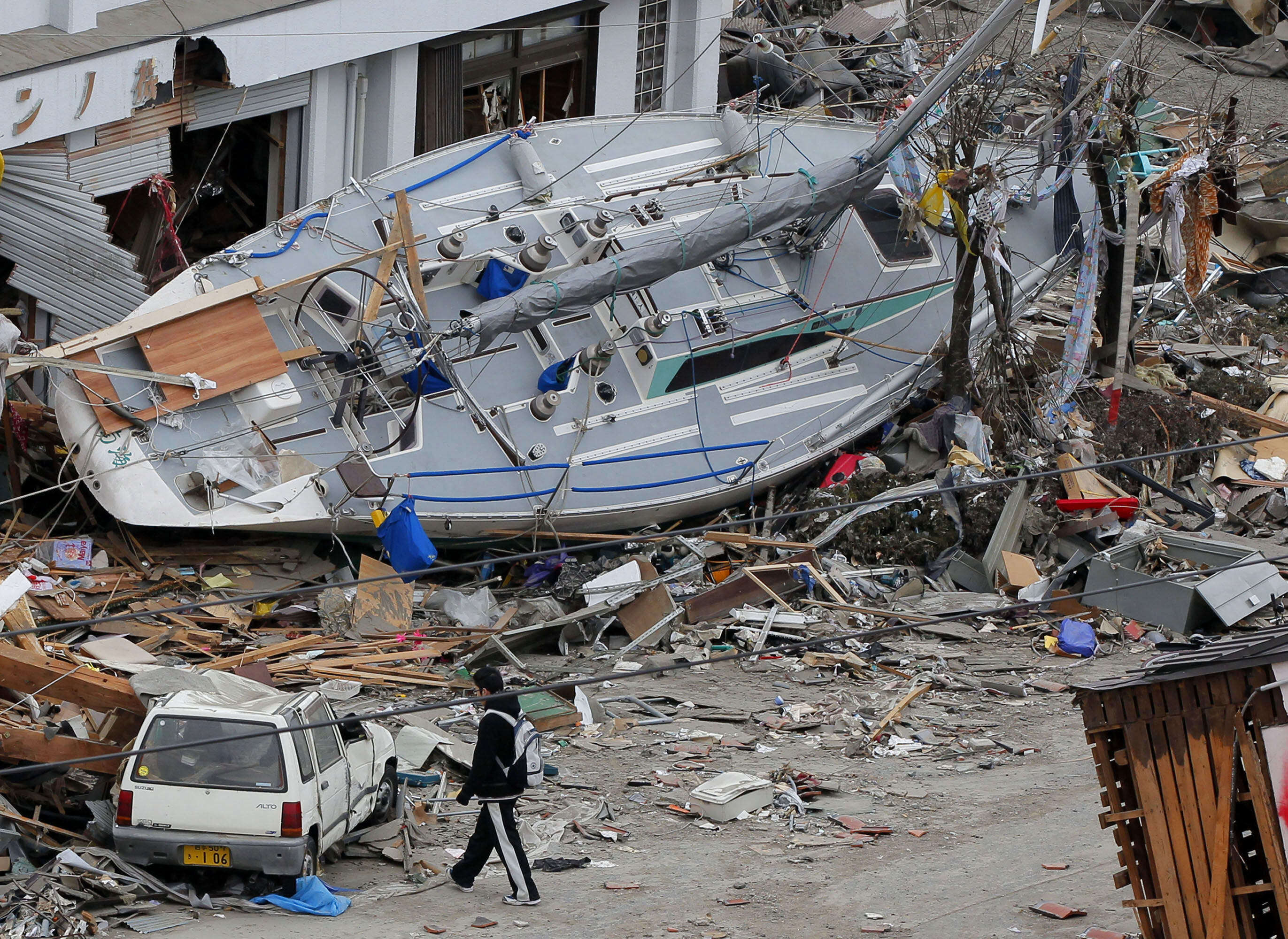 A man walks near a stranded yacht in the tsunami-hit area in Ofunato, Iwate Prefecture, Japan, March 15, 2011, four days after the disaster. 