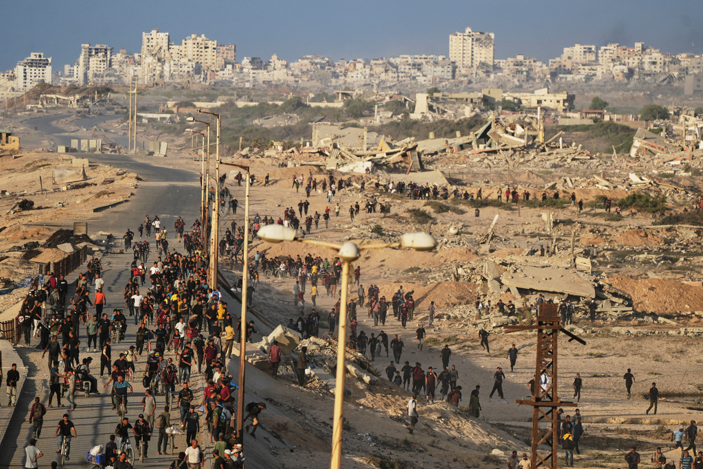 Israeli tanks are positioned on the coastal road leading to Gaza City as displaced Palestinians gather near Wadi Gaza in the central Gaza Strip.