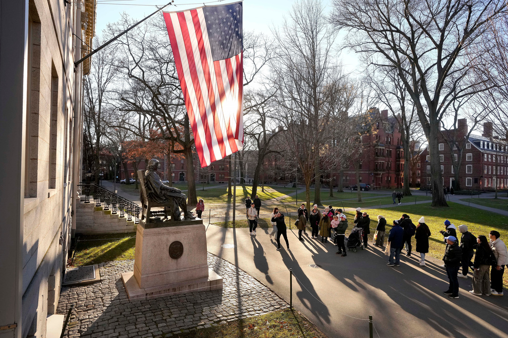 FILE - People take photos near a John Harvard statue, left, on the Harvard University campus, Jan. 2, 2024, in Cambridge, Mass. 