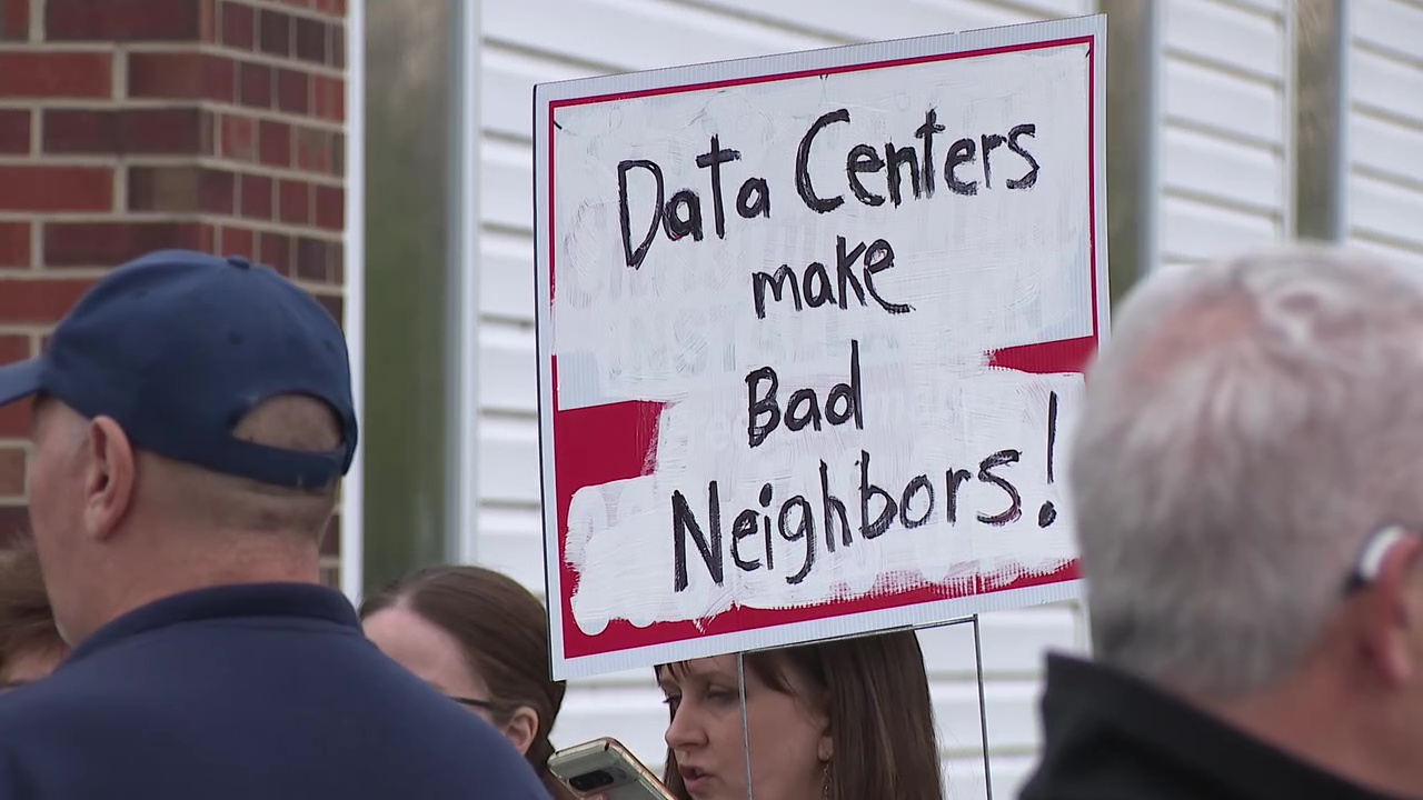 A data-center opponent holds a protest sign outside the Perry Village Municipal Complex on Thursday, April 9.