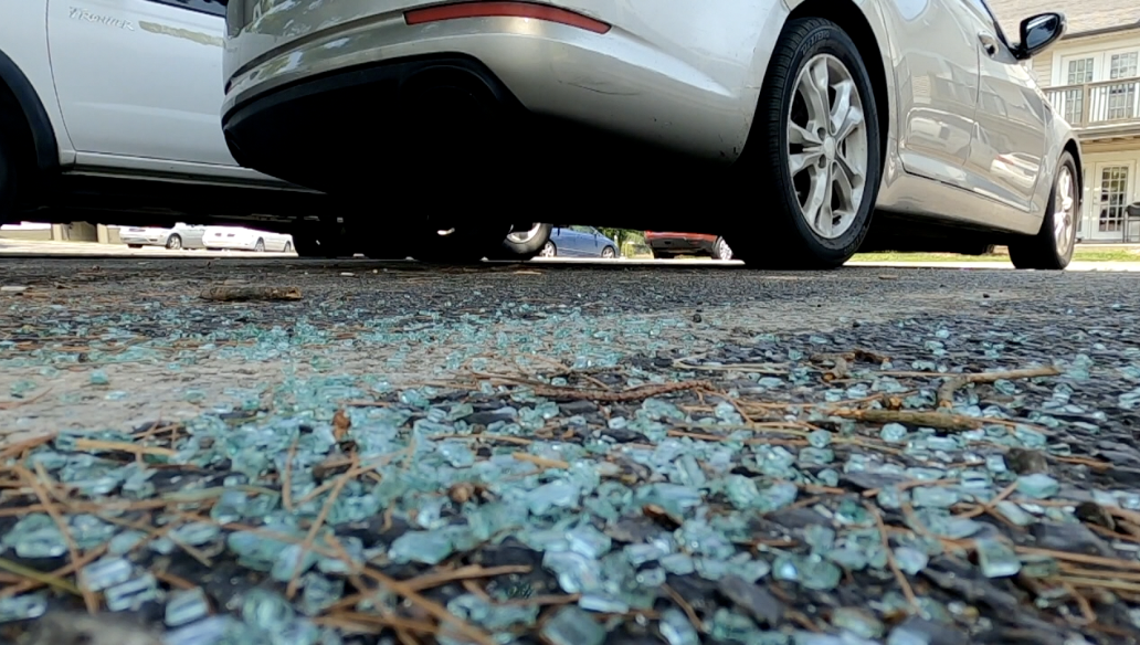 Shattered glass sits next to a parked car