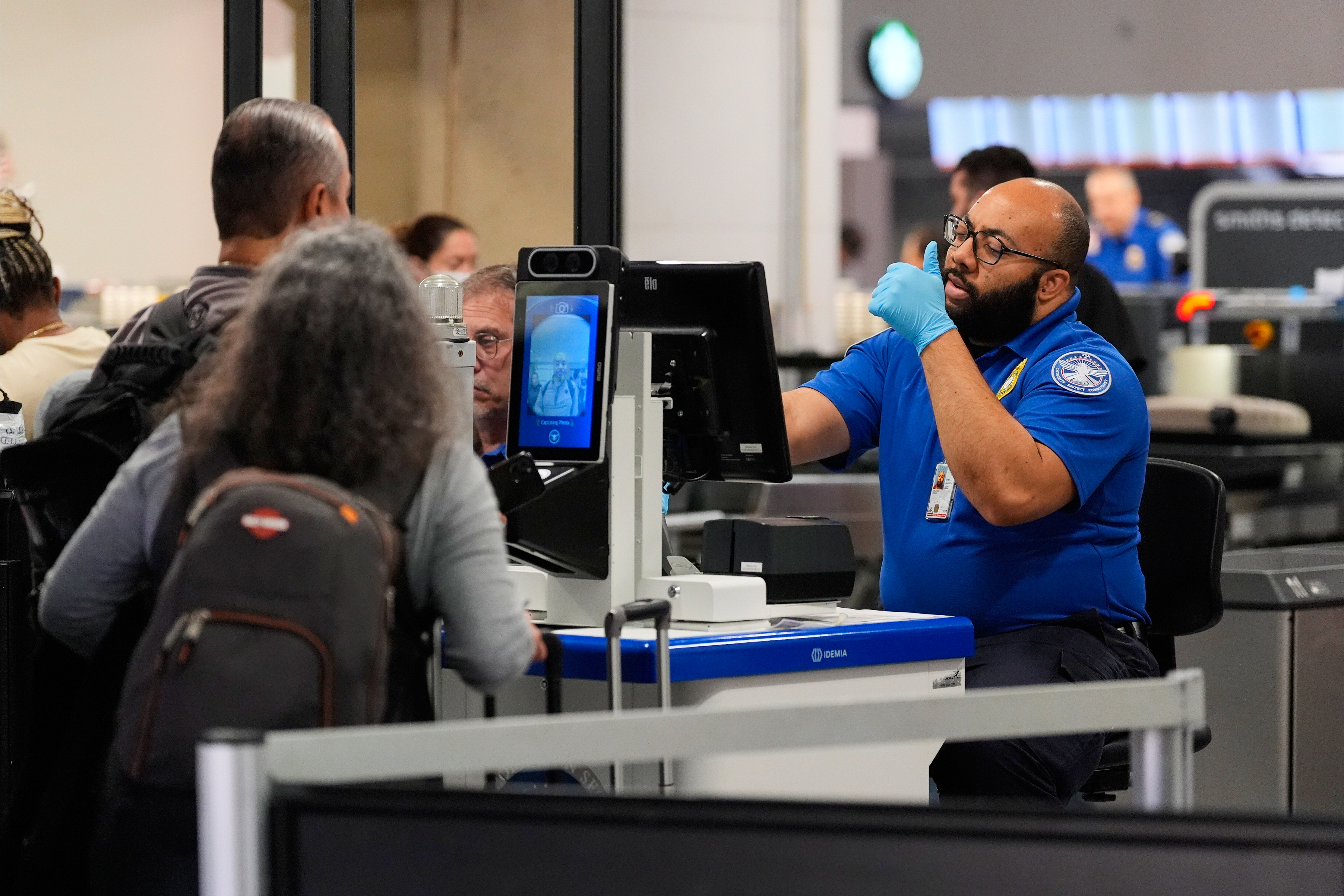 A TSA agent assists a traveler at a security checkpoint at Dallas Fort Worth International Airport, Friday, Nov. 21, 2025, in Texas. 