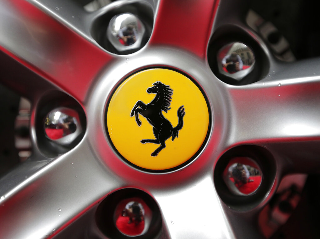 FILE - This Monday, Oct. 9, 2017 file photo shows a Ferrari logo on a car outside the New York Stock Exchange in New York. Luxury sportscar maker Ferrari says its chief executive, Louis Camilleri, has resigned for personal reasons. Chairman John Elkann will take over until a successor is named, Ferrari said in a statement late Thursday, Dec. 10, 2020. 