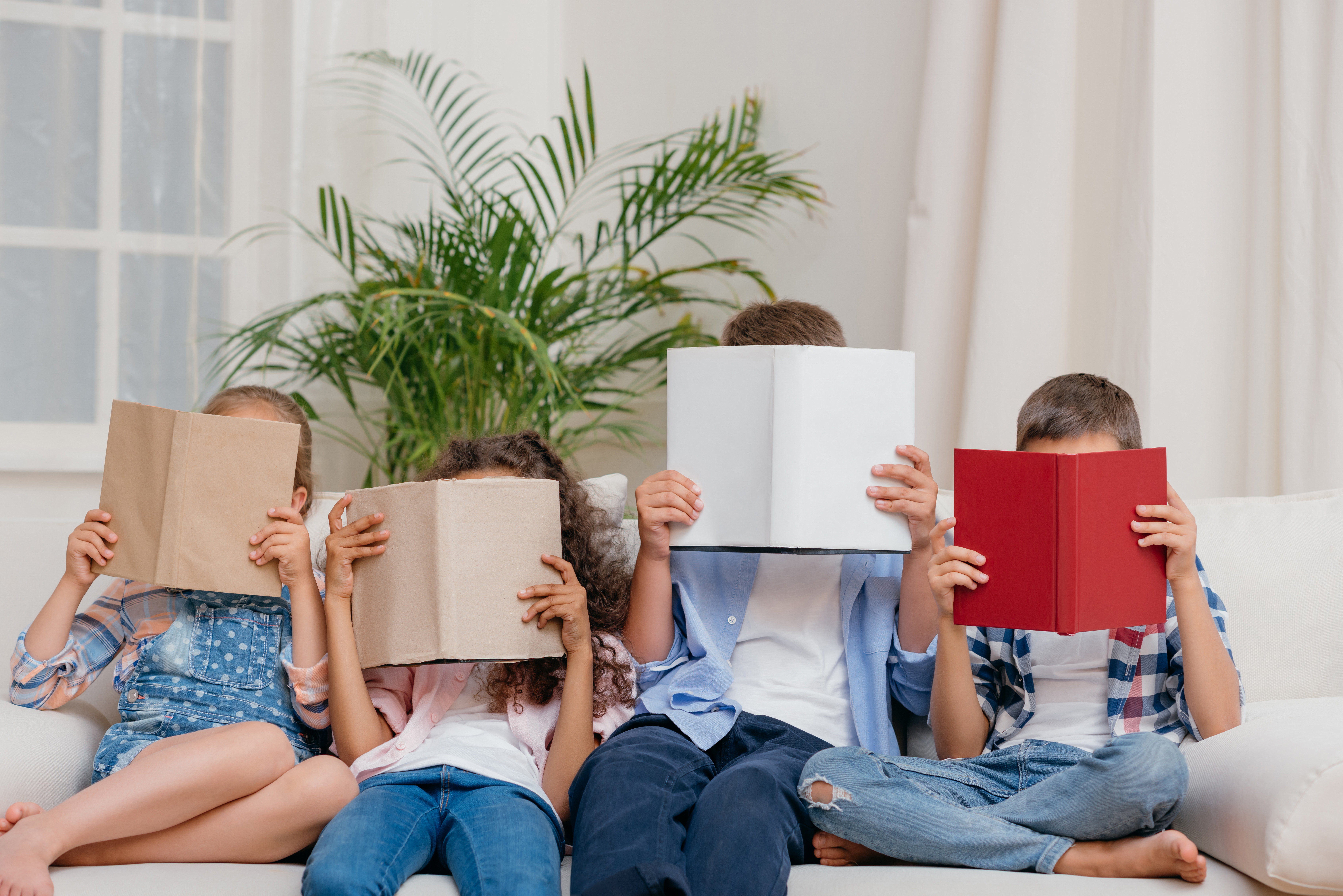 Children reading books on a couch.